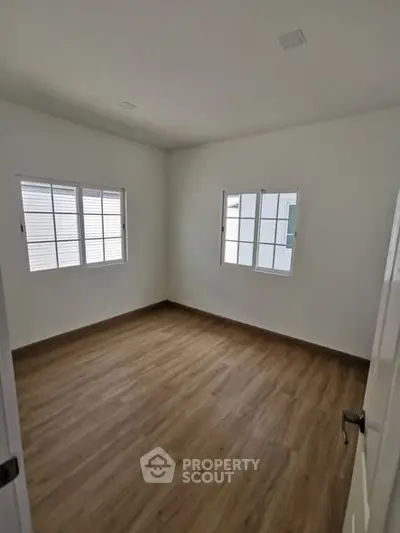 Spacious empty room with wooden flooring and large windows