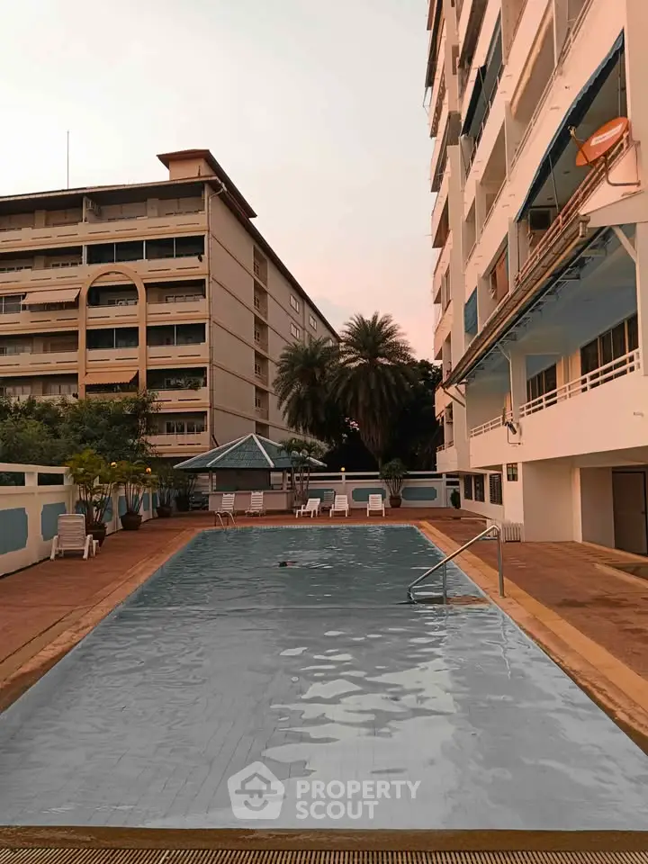 Luxurious apartment complex with a serene outdoor pool and spacious lounging area.