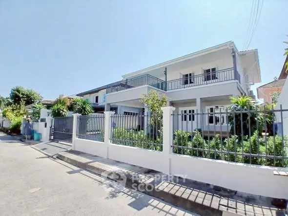 Stunning two-story house with lush garden and modern fence in a serene neighborhood.