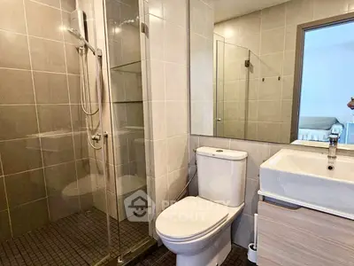 Modern bathroom with glass shower and sleek fixtures in contemporary apartment.