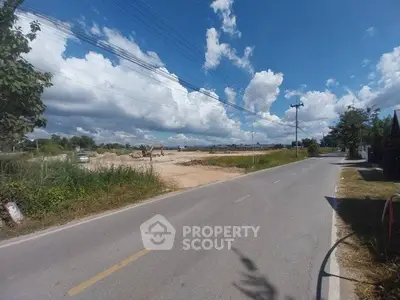 Scenic road view with clear skies and open land, ideal for development.