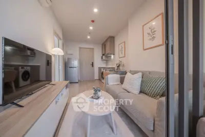 Modern living room with stylish decor, cozy sofa, and sleek kitchen appliances in open layout apartment.