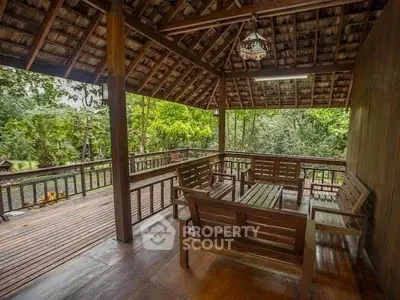 Charming wooden balcony with lush forest view, perfect for relaxation.