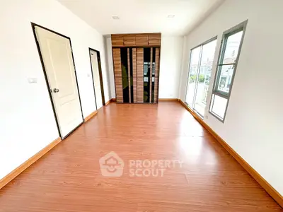 Spacious empty room with wooden flooring and large windows in modern home