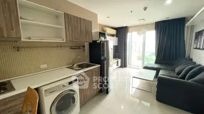 Modern open-layout kitchen and living room with washing machine and large windows.