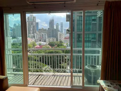 Stunning city view from modern apartment balcony with glass sliding doors.