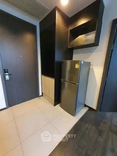 Modern apartment entryway with sleek fridge and stylish cabinetry