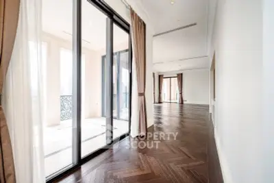 Luxurious open-plan living room with elegant hardwood floors and large glass doors leading to a balcony.