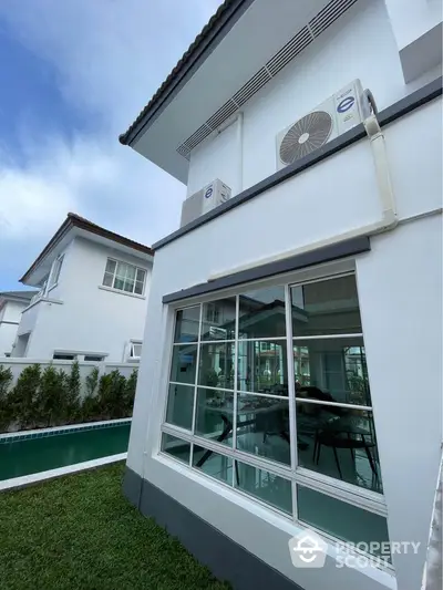 Modern two-story house with large windows and poolside view