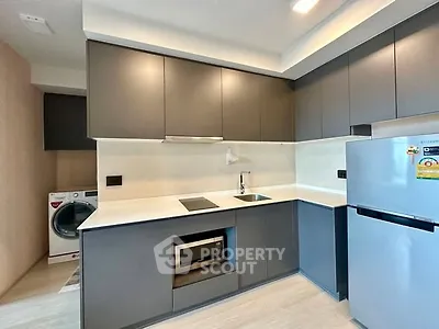 Modern kitchen with sleek cabinetry and built-in appliances, featuring a washing machine and fridge.