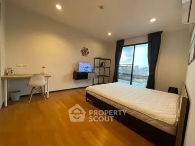 Spacious bedroom with modern decor and city view balcony access.