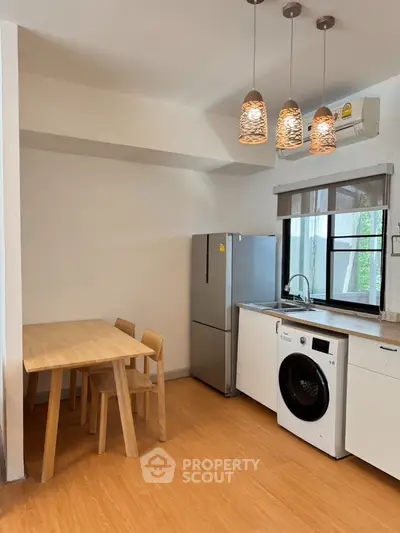 Modern kitchen with dining table, fridge, and washing machine in stylish apartment