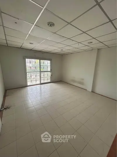 Spacious empty room with tiled floor and large window, ideal for customization.