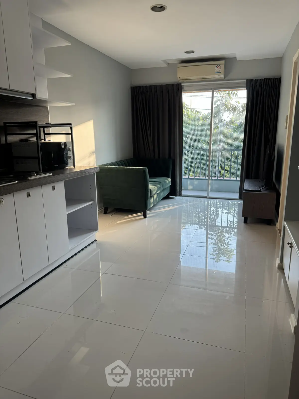 Modern living room with sleek kitchen and balcony view, featuring glossy tile flooring and stylish furniture.