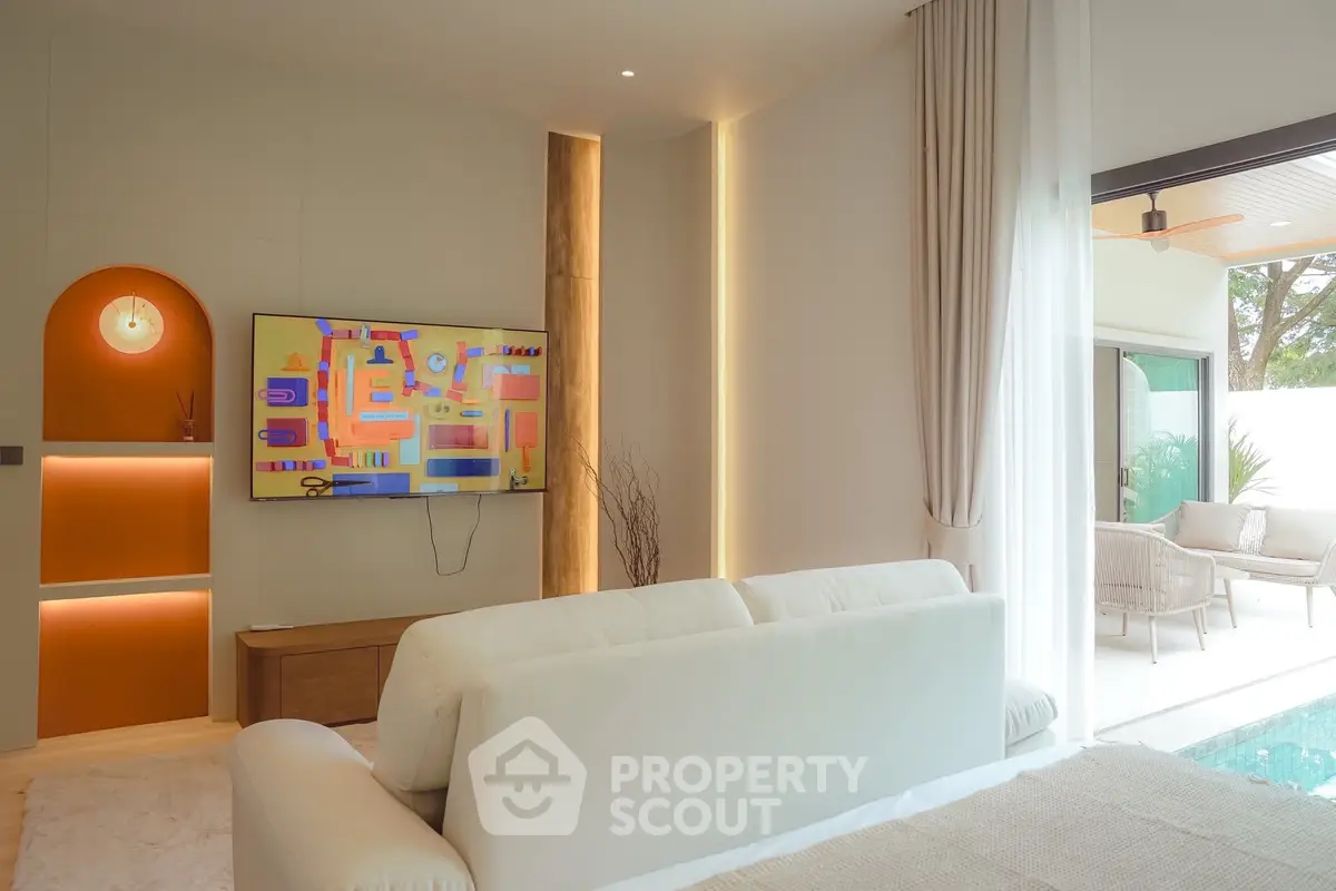 Modern living room with stylish decor and large TV, opening to a bright outdoor patio.