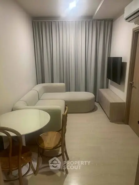 Modern living room with cozy sofa, round table, and wall-mounted TV in a stylish apartment.