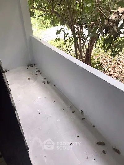 Charming small balcony with leafy view, perfect for relaxation and enjoying nature.