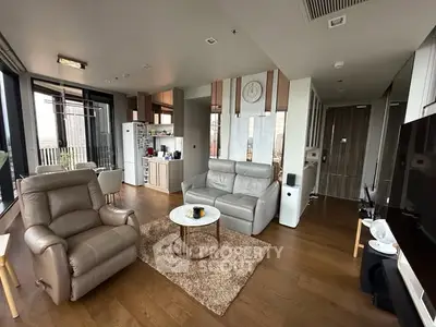 Modern living room with open kitchen, featuring stylish furniture and wooden flooring.