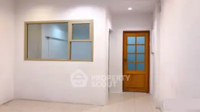 Spacious interior with tiled flooring and wooden door, ideal for customization.