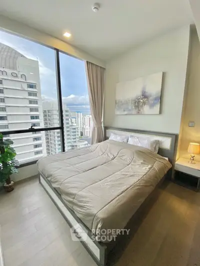 Modern bedroom with large window offering stunning city view in high-rise apartment.