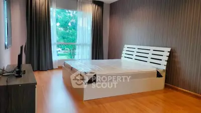 Spacious bedroom with modern decor and large window offering natural light.