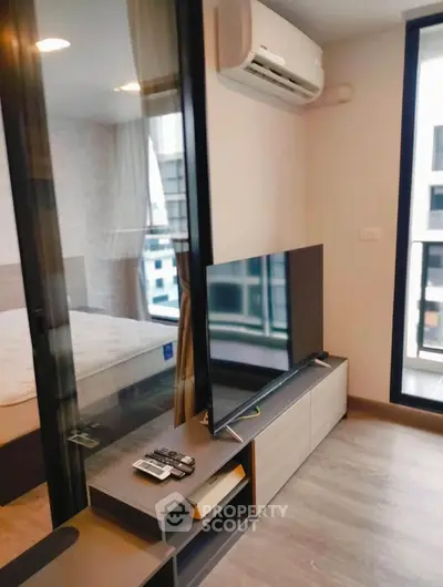 Modern living room with sleek TV setup and air conditioning in a stylish apartment.
