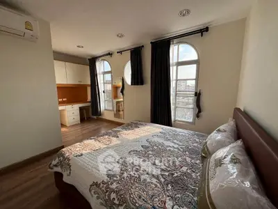 Spacious bedroom with large windows and elegant decor in a modern apartment.
