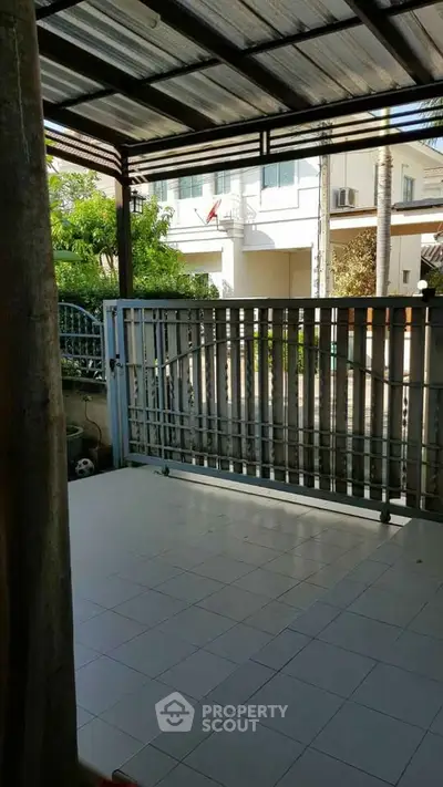 Charming covered patio with tiled flooring and metal gate, perfect for outdoor relaxation.