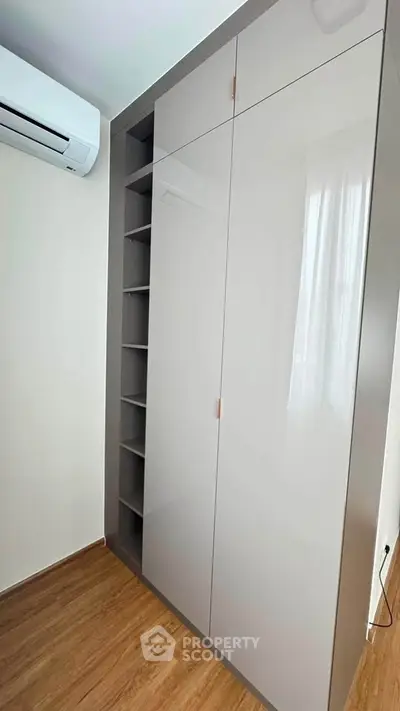 Modern bedroom with sleek built-in wardrobe and air conditioning unit.