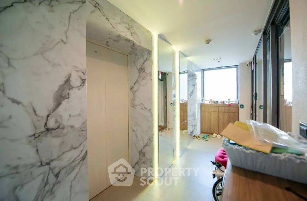 Modern apartment entrance with marble walls and sleek elevator design