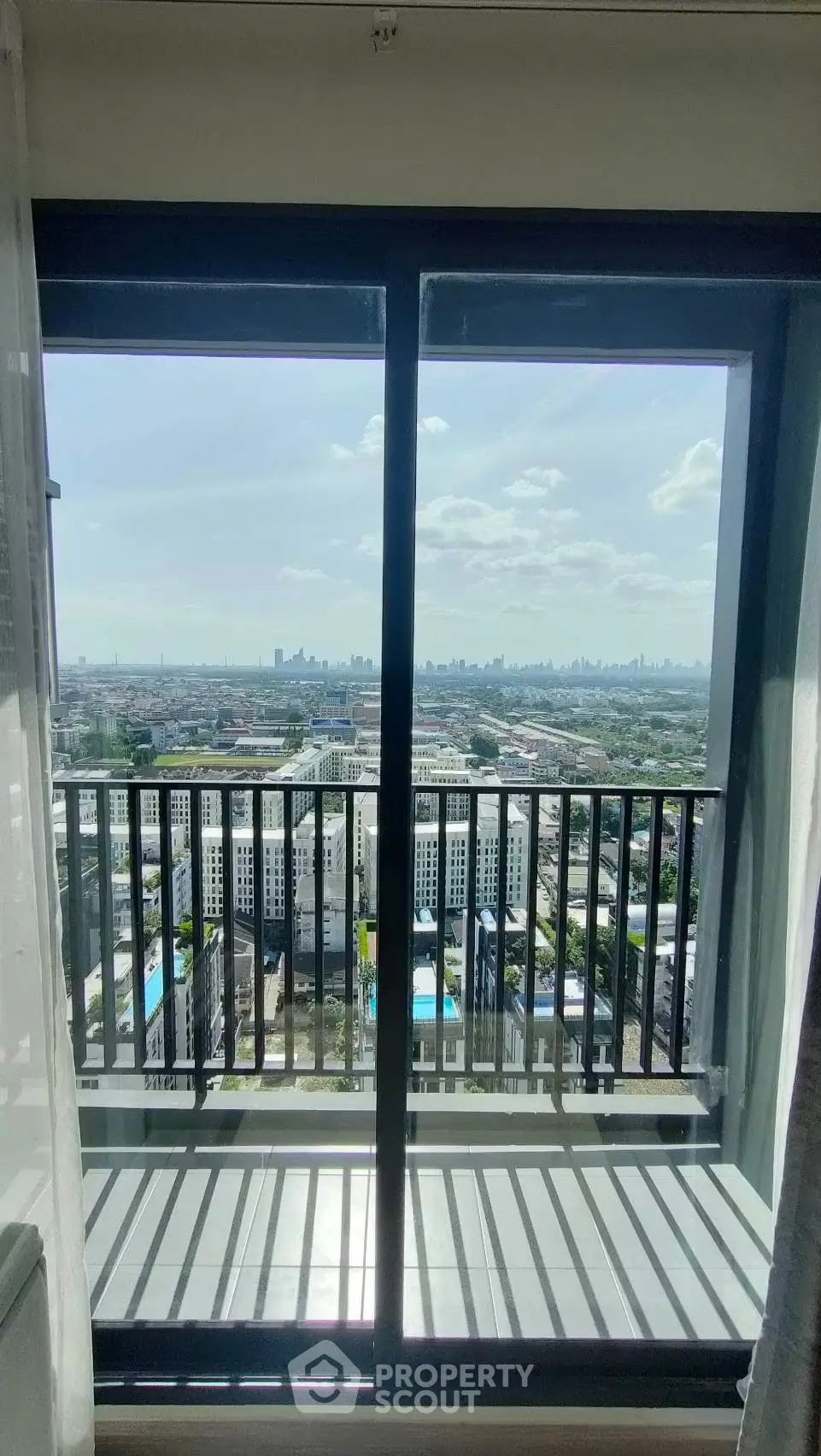 Stunning cityscape view from a modern apartment balcony with clear skies.
