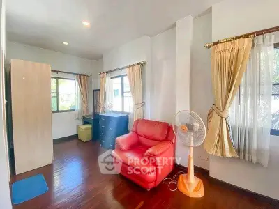 Spacious living room with red armchair and natural light, perfect for relaxation.