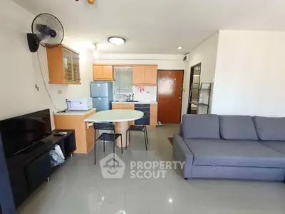 Modern open-plan living room with kitchen, featuring sleek furniture and appliances.
