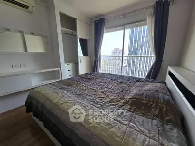 Modern bedroom with large window and city view, featuring sleek built-in storage and stylish decor.