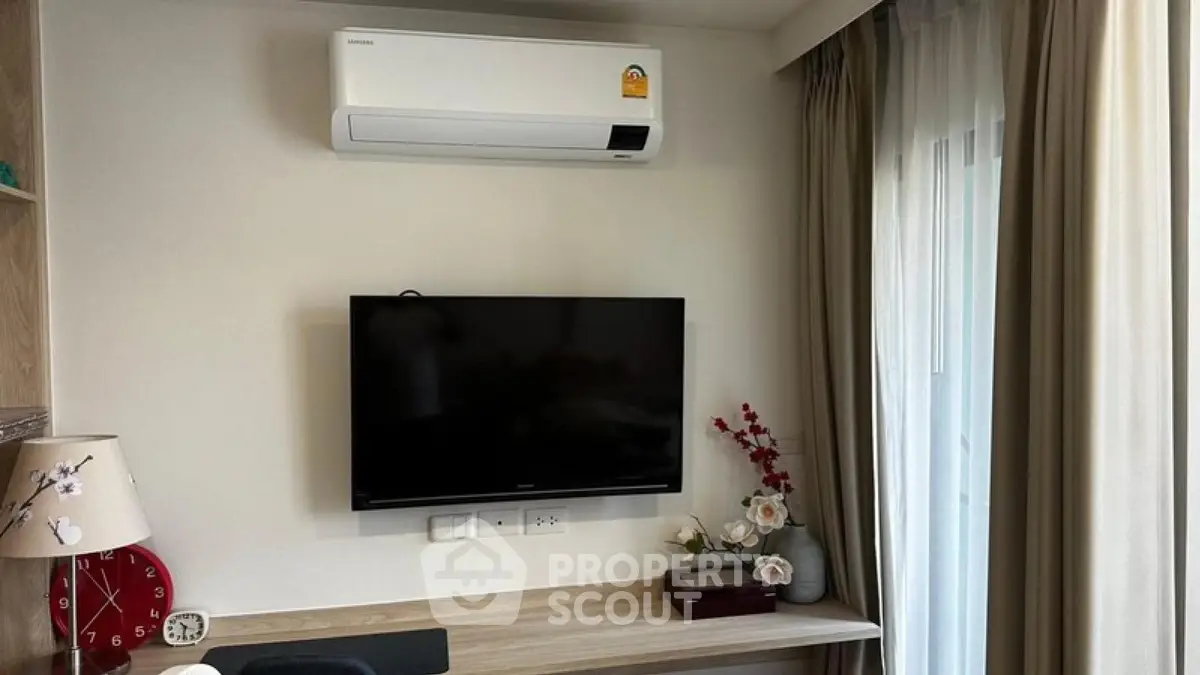 Modern living room with wall-mounted TV and air conditioner, elegant decor and natural light.