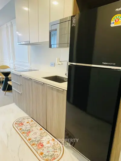 Modern kitchen with sleek cabinetry and black refrigerator in stylish apartment.