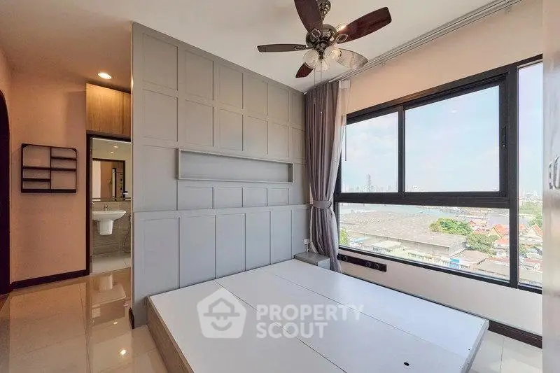 Modern bedroom with large window and city view, featuring sleek design and ceiling fan.