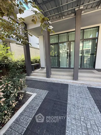 Modern building entrance with stylish tiled pathway and lush greenery
