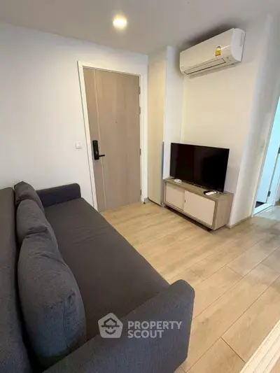Modern living room with sleek sofa, TV, and air conditioning in a cozy apartment.