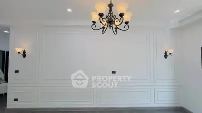 Elegant living room with classic wall paneling and stylish chandelier lighting.