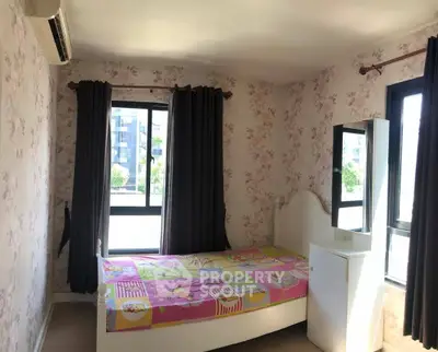Charming bedroom with floral wallpaper and large windows offering natural light.
