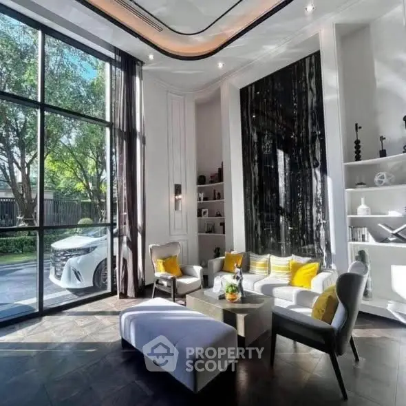 Luxurious living room with high ceilings, large windows, and elegant decor overlooking a garden view.