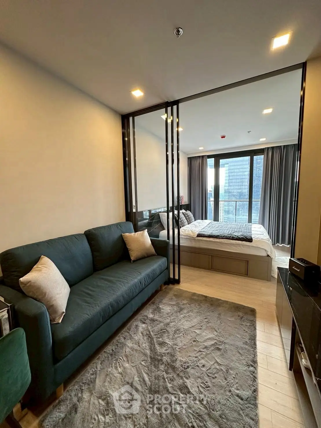 Modern studio apartment with glass partition, cozy living area, and city view balcony.