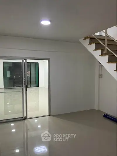 Spacious modern interior with sleek staircase and sliding glass doors, perfect for contemporary living.