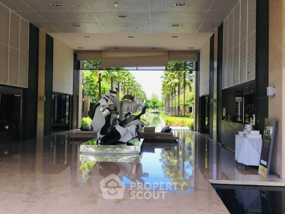Luxurious hotel lobby with modern art sculpture and palm tree garden view