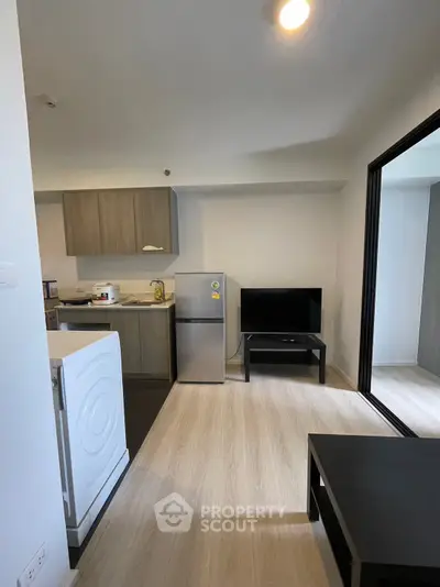 Modern apartment interior with compact kitchen and living area featuring sleek appliances and minimalist design.