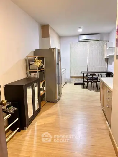 Modern kitchen with sleek cabinetry and dining area, featuring wooden flooring and contemporary decor.
