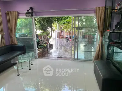 Spacious living room with glass doors opening to a lush garden view, perfect for relaxation.