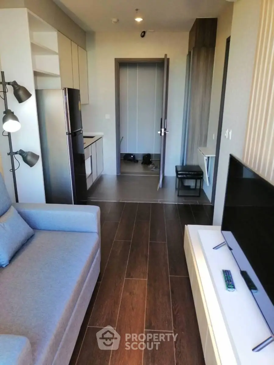 Modern living room with sleek furniture and open kitchen layout in a stylish apartment.