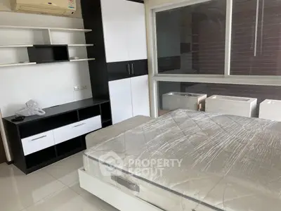 Modern bedroom with sleek built-in storage and large window for natural light.